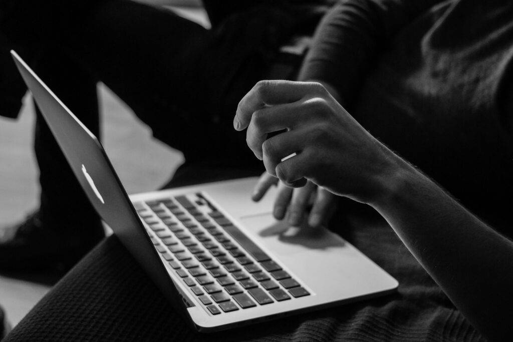 a black and white phone of someone writing on a laptop