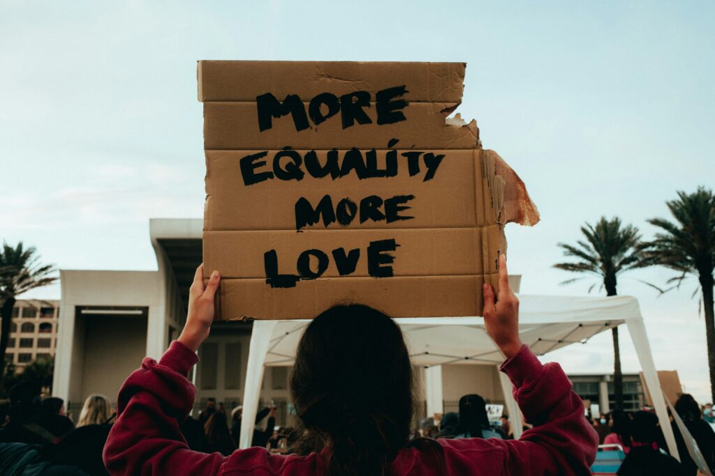 Woman holding a cardboard sign that says More Equality More Love - Social Justice advocacy